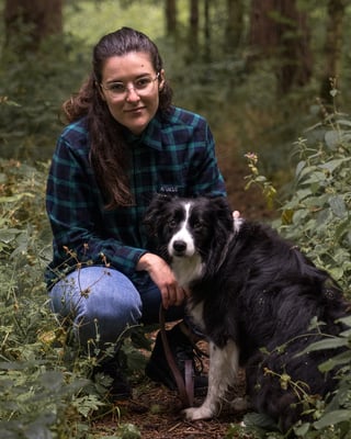 Attacus Cycling blue check adventure shirt worn by a person crouching in woodland beside a black and white collie.