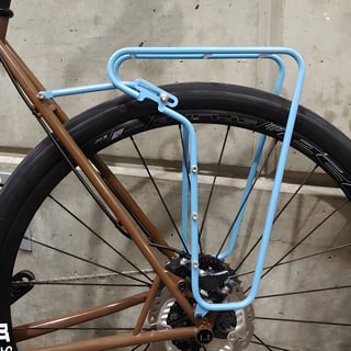 Pass and Stow light blue steel rear rack fitted to a brown bike with disc brakes, seen from the side.