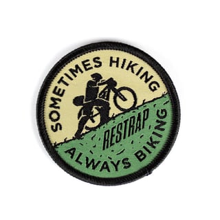 Restrap woven patch showing a rider pushing a bike uphill, reading 'Sometimes hiking, always biking'.