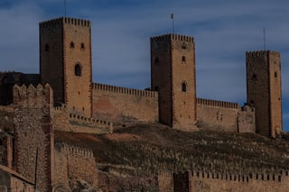 Medieval castle with tall square towers and crenellated walls on a dry hillside, passed on the European Divide Trail.