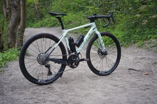 Unloaded Canyon Grizl in pale green with two bottles and a Shimano GRX 2x chainset, standing on a gravel path.