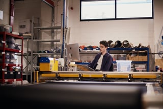 Restrap team member programs the fabric cutting machine from a computer beside its yellow gantry.