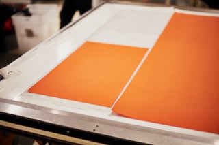 Freshly cut orange fabric panels for a custom musette laid out on the cutting machine bed at Restrap.