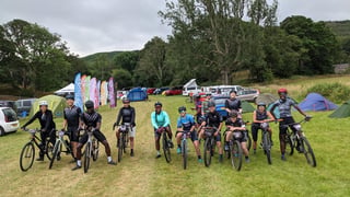 The ride4unity crew pose with their bikes and race numbers at the Grinduro 2021 campsite in Wales.