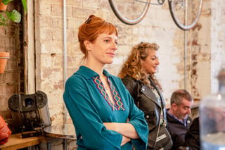 Audience member with arms folded listens to a talk in a brick-walled tap room at Bespoked 2021.