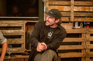 Panel speaker in a black cap and dark overshirt smiles as he listens during a Bespoked 2021 talk.