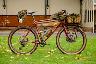 Harry Major's red Clandestine loaded with camo Wizard Works bags, a front basket and a Shazam saddle bag, on grass.