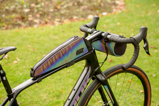 Iridescent Look and Restrap top tube bag and handlebar bag on the drop bars of a Look gravel bike.