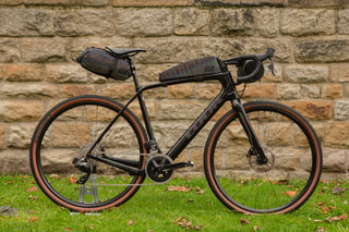 Look 765 Gravel RS with the iridescent Look and Restrap bag set against a stone wall.