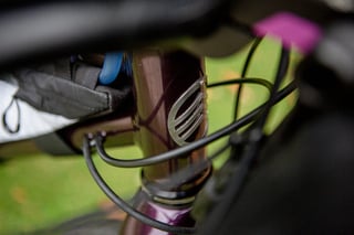 Slotted metal Lord Cycles head badge on the purple Nomad head tube, seen between the cables at Bespoked 2021.