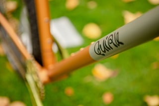 Quirk logo painted on the grey panel of the Superchub's top tube, the rest of the steel frame in copper.