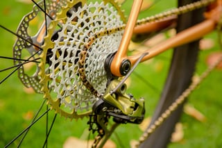 Gold and silver cassette with gold chain and green anodised rear derailleur on the Quirk Superchub.