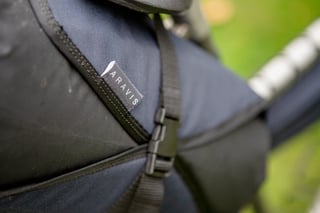 Aravis Bag Works label stitched on a navy and black saddle bag holster, beside a webbing buckle.