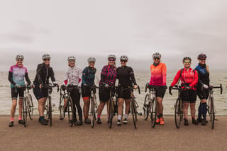 Nine women in cycling kit line up with their road bikes on the Southend seafront at the Women's Tour of Britain.