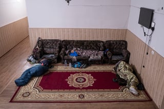 Silk Road Mountain Race riders sleeping on sofas and a rug in a guesthouse room in Talas, Kyrgyzstan.