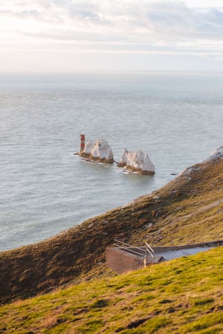 The Needles chalk stacks and red-striped lighthouse seen from the cliff above on the Isle of Wight.