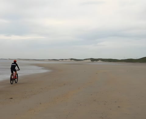 Rider cycles across the empty sands of Druridge Bay in Northumberland, venue for Sandblasted Beach Racing.