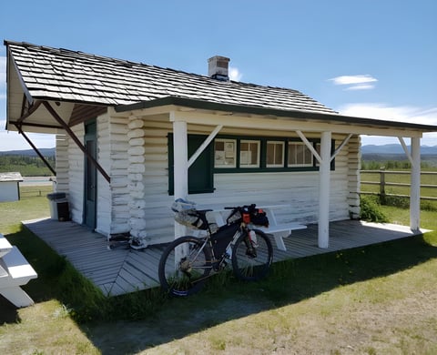 Loaded Salsa Fargo parked on the porch of a white log cabin in Canada before the 2016 Tour Divide.