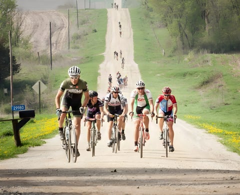 Riders climb a long gravel road in a photograph from Gravel Cycling: The Complete Guide by Nick Legan.
