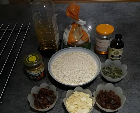 Ingredients for homemade energy bars, including oats, dates, nuts and honey, laid out on a counter.