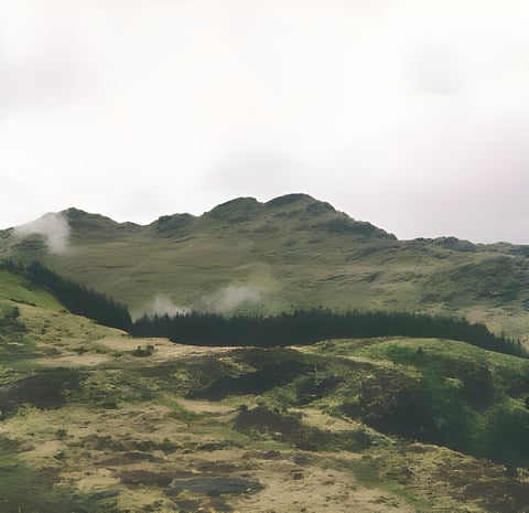 Green Scottish Highlands hillside with patches of low cloud, the kind of terrain the Highland Trail 550 crosses.