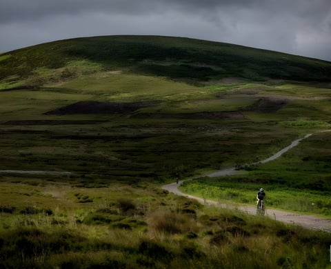 Rider on a gravel bike follows a track across green moorland during Yorkshire True Grit in the North York Moors.