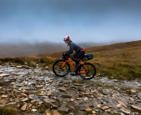 Naomi Freireich rides a loaded orange Mason Bokeh across wet, rocky moorland on the Scottish coast to coast route.