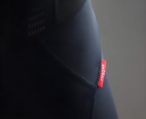 Close-up of the red Galibier label on the side seam of the black Classique Bib Shorts.