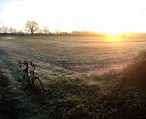 Drop-bar commuting bike stands at the edge of a frosty field at sunrise on an off-road ride to work.