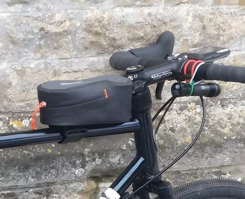 Ortlieb Cockpit Pack top tube bag mounted behind the stem of a black bike, beside a handlebar light.