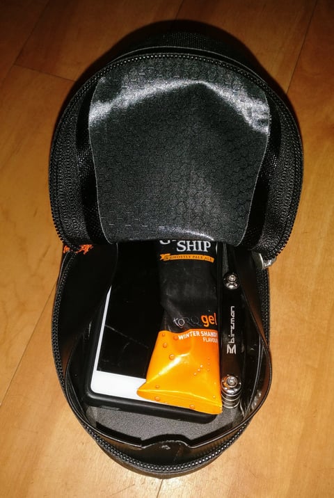 Ortlieb Cockpit Pack unzipped, holding a phone, an energy gel and a Birzman multi-tool.