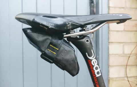 Rear view of the Apidura Expedition Tool Pack, yellow light attachment point facing out, on an orange drop-bar bike.