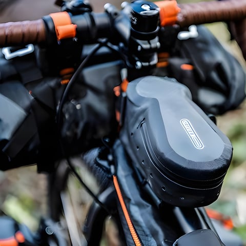 Ortlieb Cockpit Pack top tube bag with its logo, fitted on a bikepacking setup with handlebar bags.