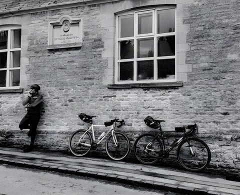 A rider leans on a stone wall beside a Surly Midnight Special and All-City Macho Man on the Cambridge Pork Pie Audax.