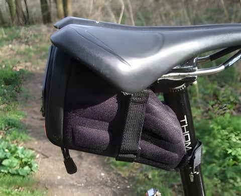 Passport Frequent Flyer seat pack strapped under a saddle and to the seatpost on a woodland trail.