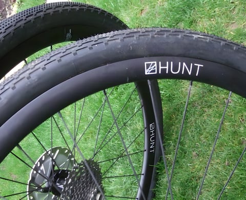 Hunt 30 Carbon Gravel Disc wheels with tyres fitted, resting on grass with centre-lock rotor and cassette.