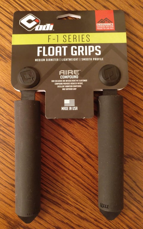 ODI F-1 Float grips, the smooth-profile version of the F-1 Series, in their packaging on a wooden table.