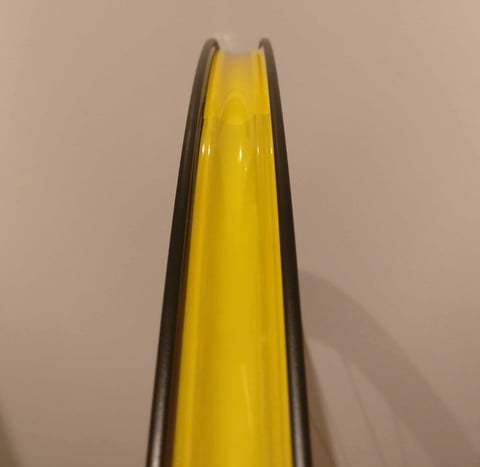 Edge-on view of a bare Hunt 30 Carbon Gravel rim, with yellow tubeless rim tape visible in the rim bed.