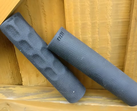 A contoured ODI F-1 Vapor grip and a smooth F-1 Float grip leaning side by side against a wooden fence.