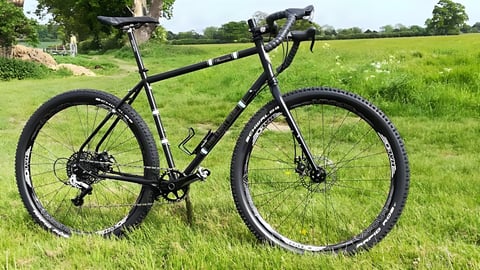 Light Blue Darwin One By MT drop-bar 29er with 2.25in tyres, parked in a grassy field.