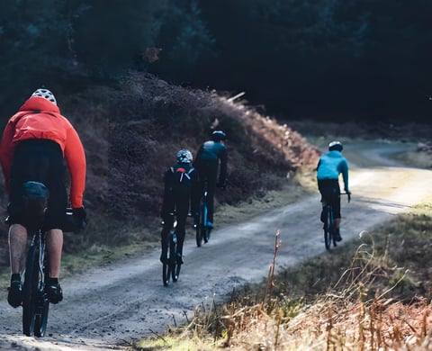 Four riders on a gravel forest road on the recon for The Distance, a bikepacking weekend in the Peak District.