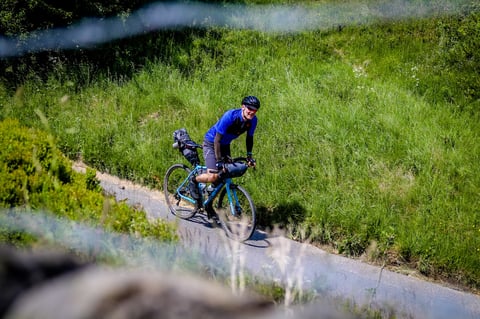 Rider on a gravel bike loaded with Passport bikepacking bags on a narrow lane during The Distance in the Peak District.