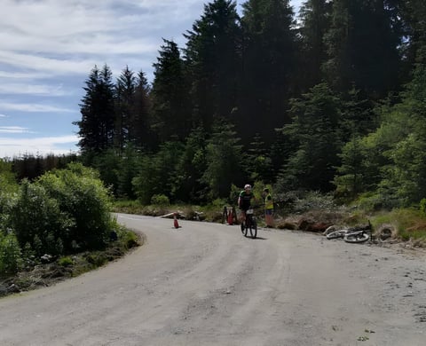 Rider passes a marshal and cones on a forest road during Gritfest 2018 near Llandovery.