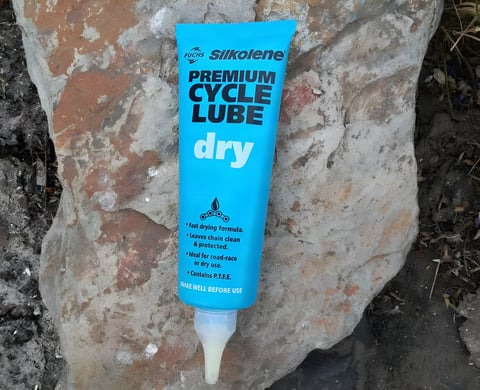 Blue tube of Silkolene Premium Cycle Lube Dry resting on a rock.