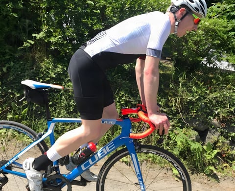 Rider in Galibier Peloton Lightweight bib shorts and a white jersey, riding a blue Cube road bike on a sunny lane.