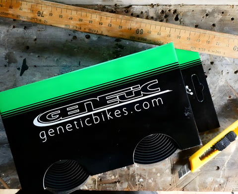 Two boxes of Genetic silicone bar tape on a workbench beside a wooden ruler and a yellow utility knife.
