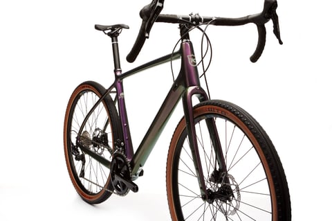 Kona Libre gravel bike in colour-shifting purple, three-quarter studio view with tan-wall WTB tyres.