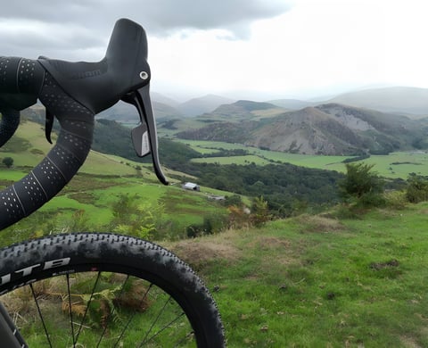 SRAM drop-bar shifter and WTB tyre on a gravel bike, with the Dyfi Forest valley in Wales beyond.