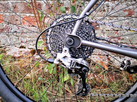 SRAM Rival rear derailleur and cassette on the Bombtrack Hook EXT, with the drivetrain's external cable run.