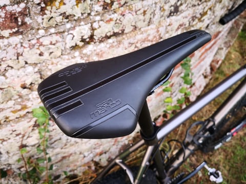 Selle San Marco Squadra saddle on the Bombtrack Hook EXT, seen from above against a lichen-covered wall.